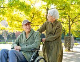 Senior im Rollstuhl mit Begleitung im Park