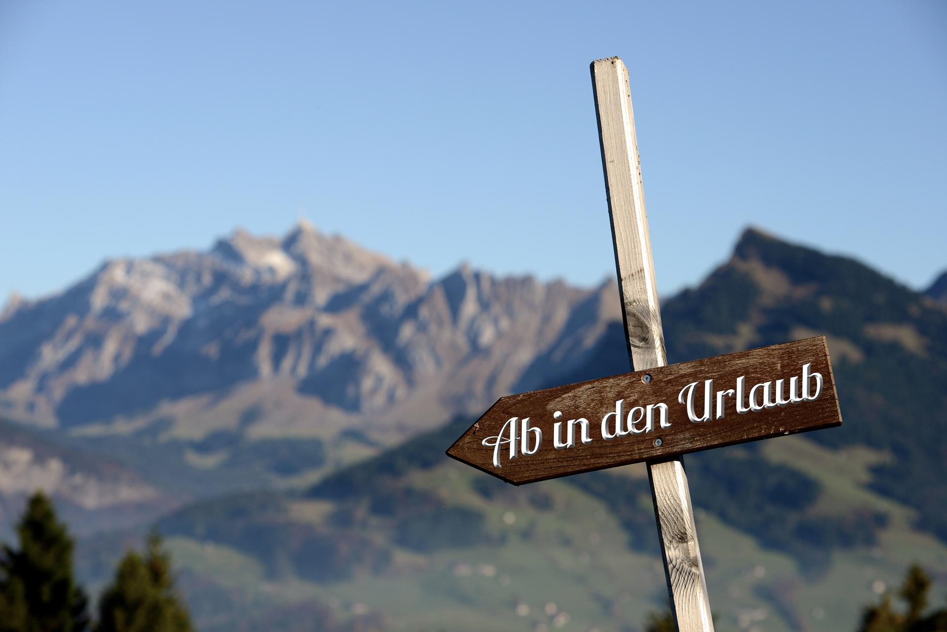 Holzschild mit Aufschrift Ab in den Urlaub vor Bergen | Hütten mieten Österreich