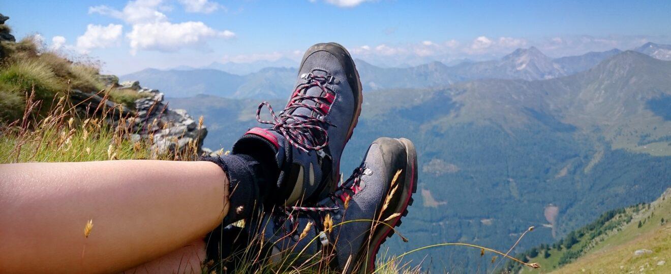 Wanderschuhe im Gras mit weitem Bergblick | Hütten mieten Österreich