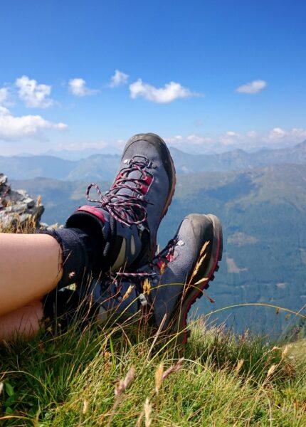 Wanderschuhe im Gras mit weitem Bergblick | Hütten mieten Österreich