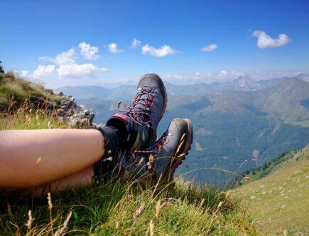 Wanderschuhe im Gras mit weitem Bergblick | Hütten mieten Österreich